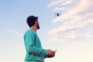 man controlling a modern drone at sunset, back view