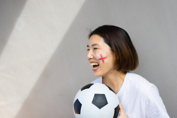 Happy asian woman with football and flag of england on her cheek