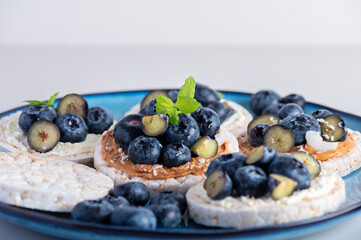 Open sandwich with blueberries. Made from rice crispbreads and peanut butter, healthy nutritious snack option, vegan food