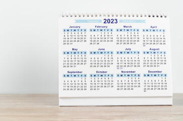 The 12 months desk calendar 2023 on wooden background.