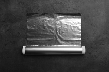 Roll of foil paper on grey table, top view