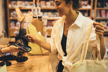 Young woman paying in a shop using credit card and terminal.