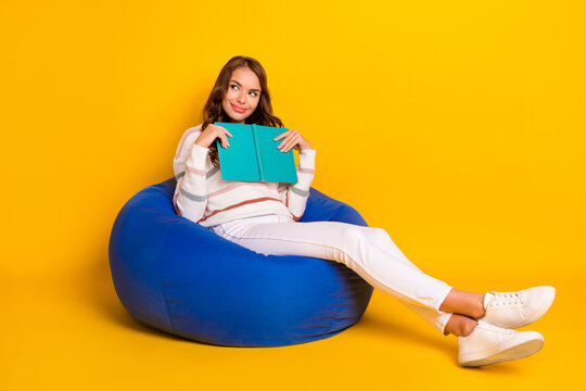 Full length body photo of young smart clever woman sitting pouf reading book interested look information isolated on yellow color background