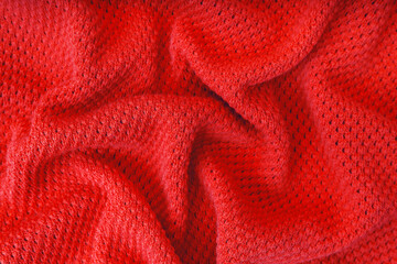 Fototapeta na wymiar Close up background of knitted wool fabric with dots pattern. Bright red color crumpled knitting wool knitwear texture. Openwork abstract knitted jersey fabric abstract backdrop