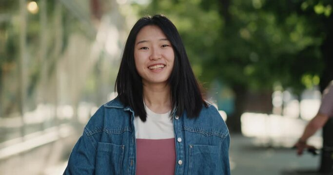 Happy Asian girl walking on a sunny city street
