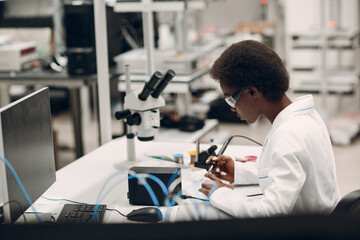 Scientist african american woman working in laboratory with soldering iron. Research and development of electronic devices by color black woman.