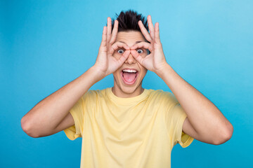 Funny cheerful guy holds hands near eyes pretends looking through binoculars shows zero okay...