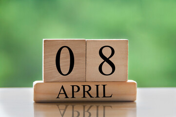 April 8 calendar date text on wooden blocks with blurred park background. Copy space and calendar concept