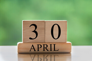 April 30 calendar date text on wooden blocks with blurred park background. Copy space and calendar...