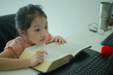 Fototapeta na wymiar Asian little girl reading bible at home. christian concept.