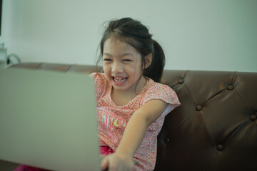 Asian girl sitting on couch with computer enjoy playing game