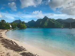 Tropical island beach, Moorea, French Polynesia. Crystal water sea bay, white sand beach, green mountain range in background. Virgin untouched nature sea lagoon, yacht tour, exotic travel destination