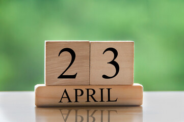 April 23 calendar date text on wooden blocks with blurred park background. Copy space and calendar concept