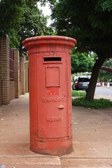 A photo of a red old mailbox in the street in front of the university of Potchefstroom.