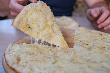 Man taking piece of pizza in cafe. Pizza with pear and cheese