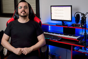 portrait of young latin male music producer sitting in his home music studio.