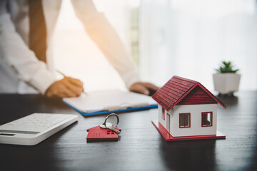 Real estate agents offer contracts to purchase or rent residential. Business person hands holding home model, small building red house. Mortgage property insurance moving home and real estate concept