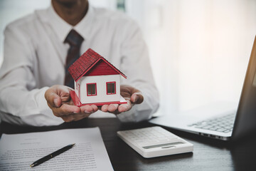 Business person hands holding home model, small building red house. Real estate agents offer contracts to purchase or rent residential. Mortgage property insurance moving home and real estate concept