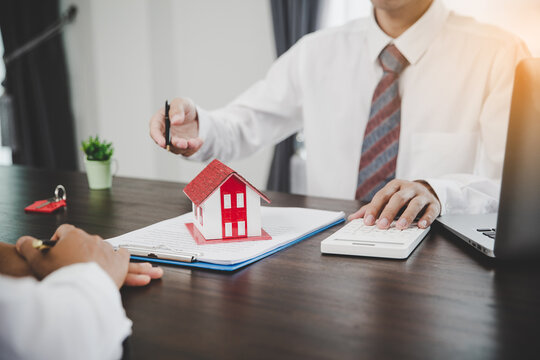 Real Estate Agents Offer Contracts To Purchase Or Rent Residential. Business Person Hands Holding Home Model, Small Building Red House. Mortgage Property Insurance Moving Home And Real Estate Concept