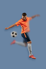 Fototapeta na wymiar Portrait with blurring effect. Young male soccer or football player kicking ball for the goal in jump. Concept of sport, World Cup tournament