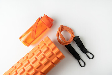 Different colourful equipment for fitness and sport exercises orange dumbbells and expanders, fitness balls and bands lying on a white background
