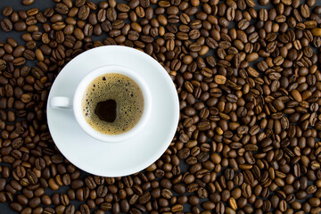 Top view of black coffee in the white cup and coffee beans. Close-up. Copy space.