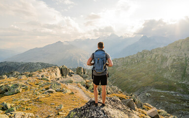 Hiker at the top of the pass with a backpack to enjoy a sunny day in the Alps. Mountain lake nearly...