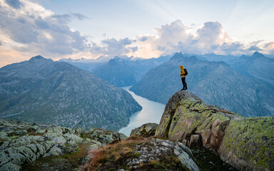 Adventurous man hiker standing on top of a rocky mountain overlooking the dramatic landscape at...