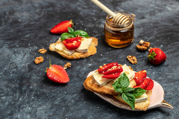 Two toasts or bruschetta with strawberries, cheese camembert nuts and honey. Summer breakfast....