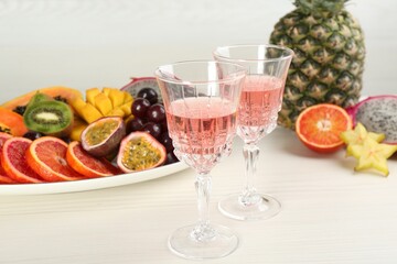 Delicious exotic fruits and wine on white wooden table