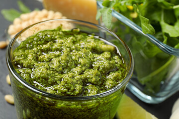 Glass of tasty arugula pesto on table, closeup