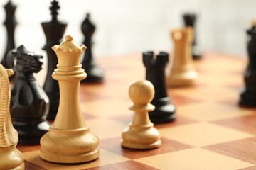 Chessboard with game pieces on light background, closeup
