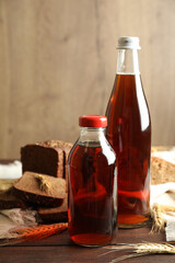 Bottles of delicious fresh kvass, spikelets and bread on wooden table