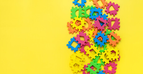 Soft children's multi-colored jigsaw puzzles with various figures inside on yellow background flat lay top view. Children's creativity games development of thinking logic education Abstract background