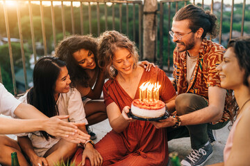 Friends surprise a birthday girl with a cake at the rooftop party.