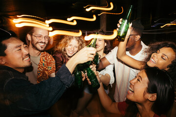 A group of friends is celebrating and toasting with beer at a night party.