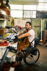 A craftsman with disability sits in a wheelchair in his own workshop. - 524288698