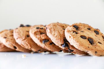 Delicious chocolate chip cookies lined up on white table, a tasty biscuit snack, selective focus