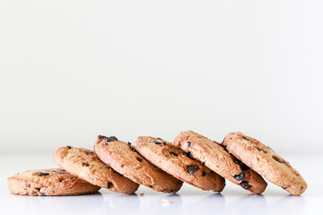 Tasty biscuit snack, a line of delicious chocolate chip cookies on a white table