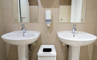 Pair of sinks in a modern public toilet with soap dishes