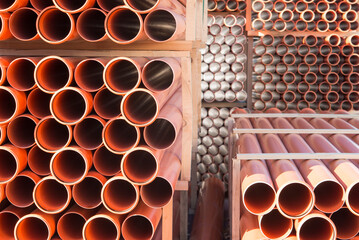 Background of orange plastic sewage pipes used at the building site. Texture and pattern of plastic drainage pipe. Light through tubes.