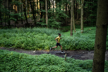 Junger dunkelhäutiger Mann in Sportkleidung läuft im Wald beim Trailrunning