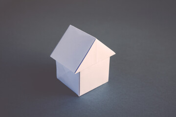 White paper house origami isolated on a grey background