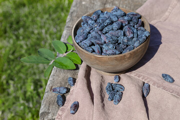 Honeysuckle in a wooden bowl on an old wooden table on a sunny day