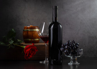 Wine, grapes and red rose on a dark background