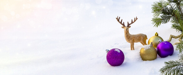 Banner with purple and gold Christmas decorations on the snow.