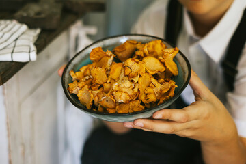 cute farmer boy in casual clothes sit at table on veranda of country village house with vegetables and chanterelle mushrooms, eco-friendly food from garden, autumn harvesting