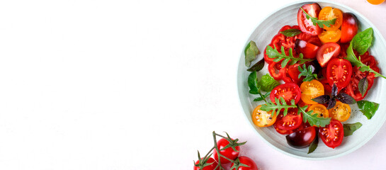 Web banner with salad with red, black and yellow cherry tomatoes, arugula and basil served on wheat straw plate. Mockup with copy space. Healthy eating
