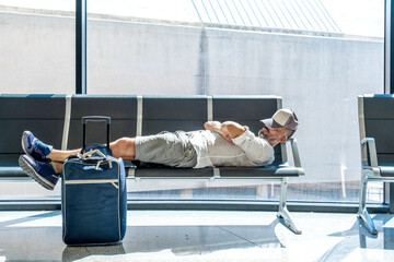 man in the airport sleeps on the armchairs - 524293468