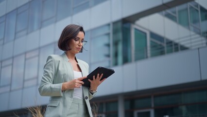Calm beautiful young woman engaged in business while going to work using tablet computer